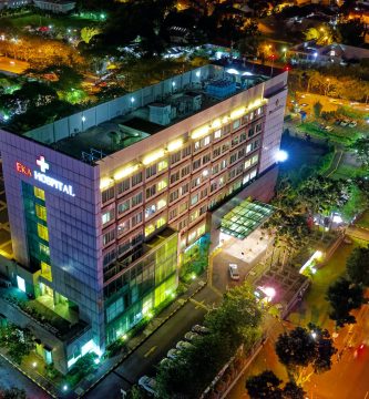 hospital beside vehicle park and road at night